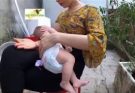 2 months old baby Thinh is breastfeeding outside backyard with having a sun tan